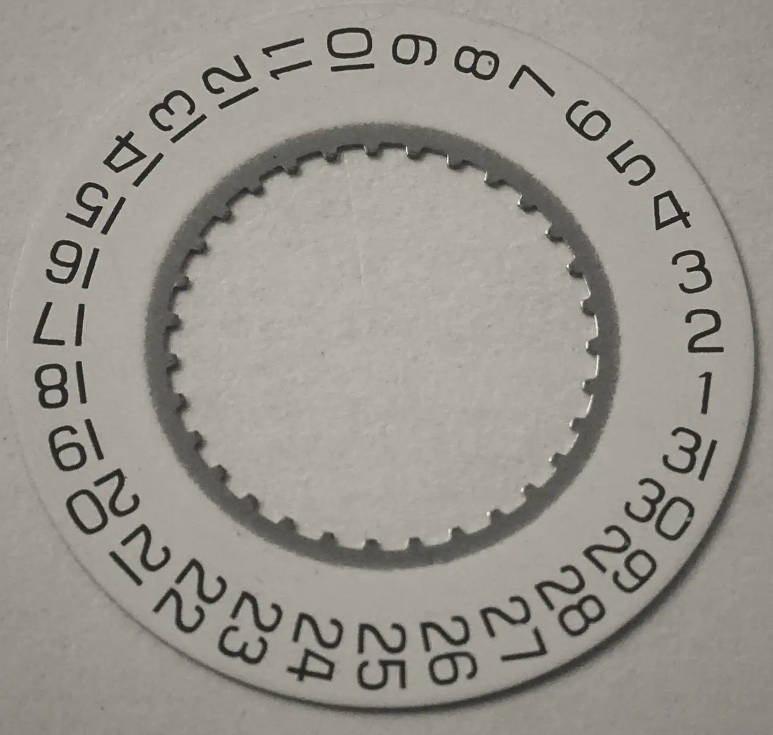 An engraved date ring, numerals cut into brushed steel.